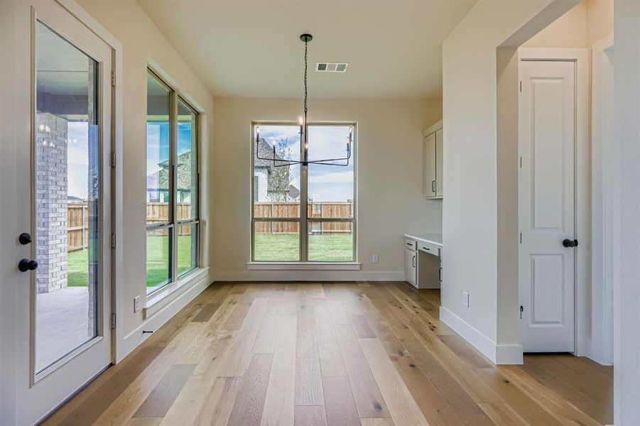Unfurnished dining area with a chandelier, light wood-type flooring, and built in study area Unfurnished dining area with a chandelier, light wood-type flooring, and built in study area