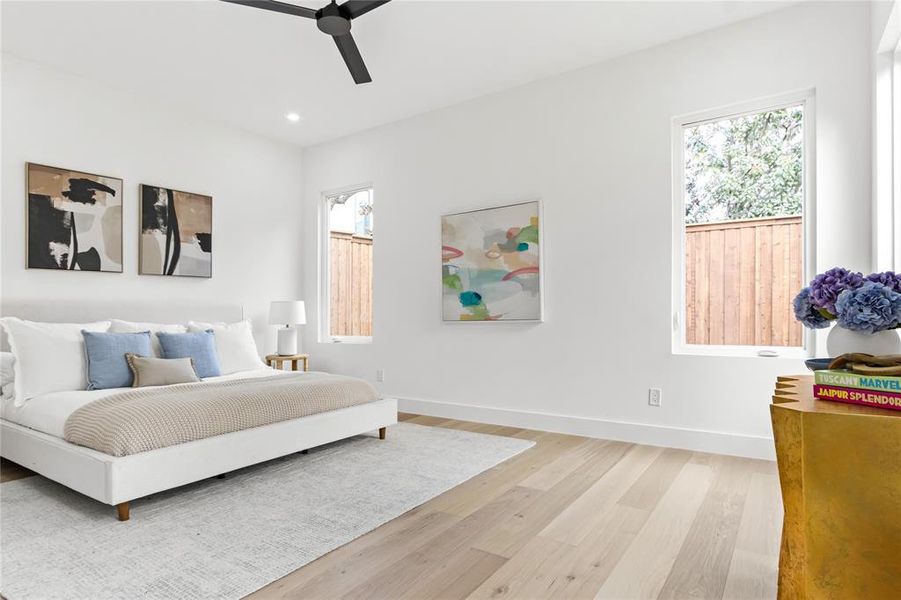 Bedroom with ceiling fan, light hardwood / wood-style floors, and multiple windows