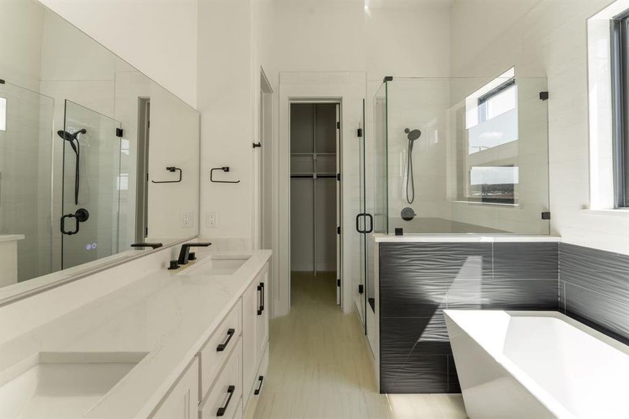 Full bath with a stall shower, double vanity, a freestanding bath, and a spacious closet
