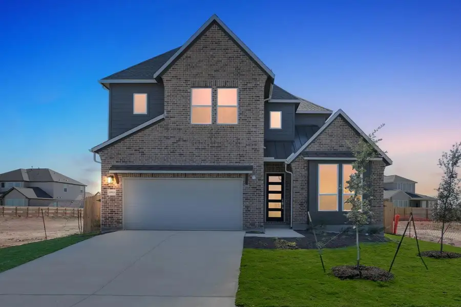 View of front of house with concrete driveway, a garage, a standing seam roof, and brick siding