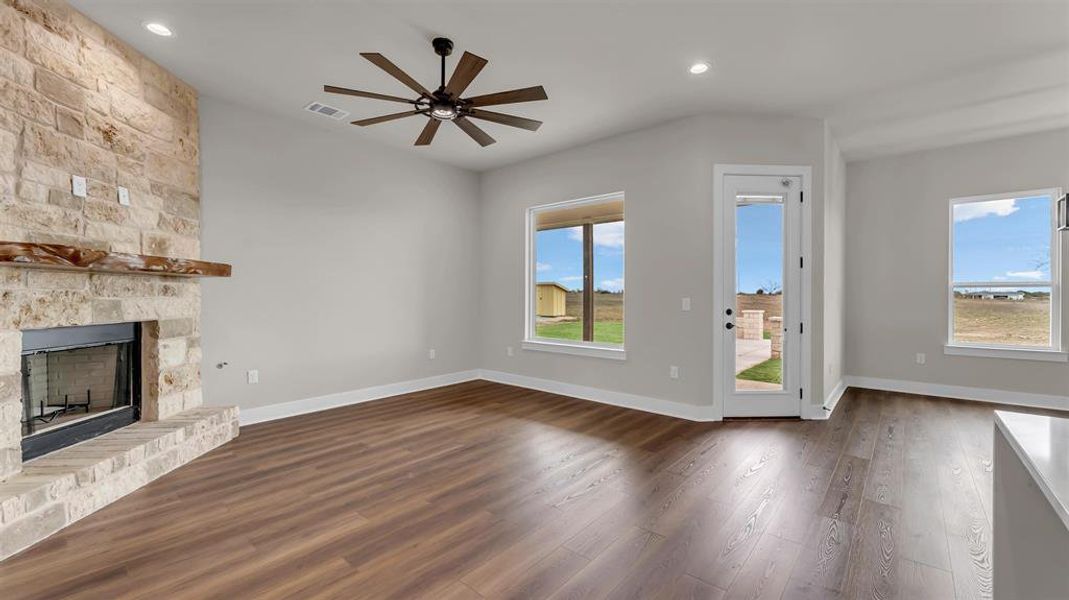 Rich wood-look flooring and a stone-clad fireplace anchor this open-concept living space. Rich wood-look flooring and a stone-clad fireplace anchor this open-concept living space.
