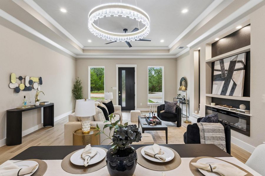 Elegant crown molding and recessed lighting adorn the ceilings, complementing the warm wood flooring throughout this spacious living area.