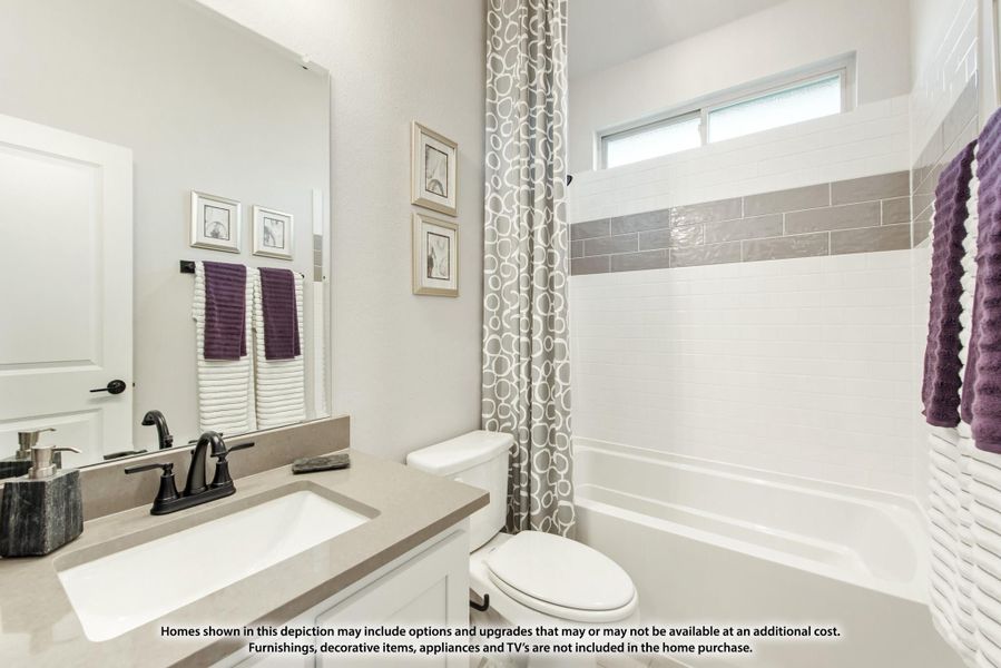 Bathroom with quartz countertop vanity, white tile tub surround with gray accent strip, and shower curtain