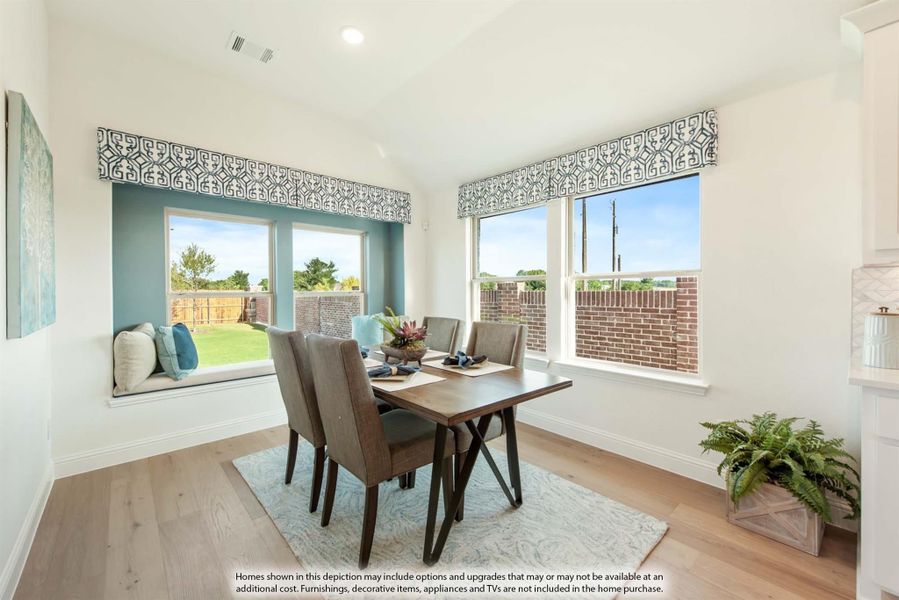 Dining area with wood table, four chairs, window seat, and large windows with backyard views on light hardwood floors