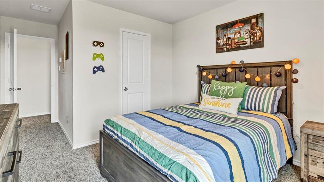 Bedroom featuring neutral wall paint, gray textured carpeting, a solid-panel door, baseboard trim, and a wood-finish bed frame with headboard Bedroom featuring neutral wall paint, gray textured carpeting, a solid-panel door, baseboard trim, and a wood-finish bed frame with headboard