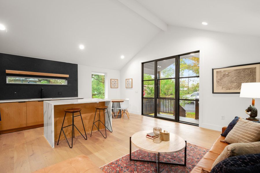 Living room featuring light wood-style flooring, recessed lighting, beamed ceiling, and high vaulted ceiling