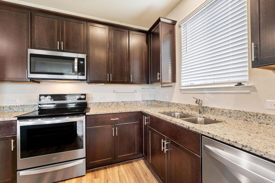 A well-appointed culinary space featuring ample dark wood cabinetry and pristine granite countertops. A well-appointed culinary space featuring ample dark wood cabinetry and pristine granite countertops.