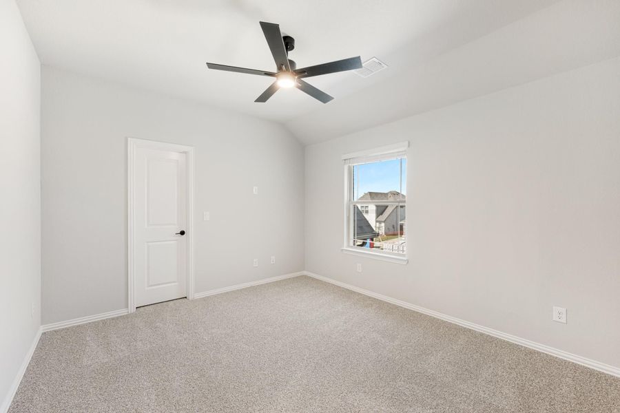 Empty bedroom with vaulted ceiling, ceiling fan, carpet flooring, and single window Empty bedroom with vaulted ceiling, ceiling fan, carpet flooring, and single window