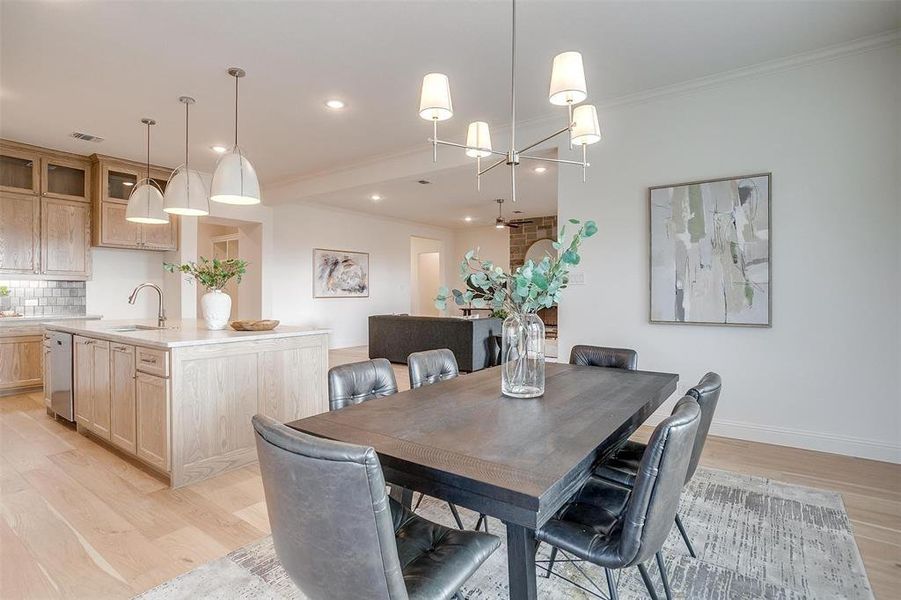 Dining space featuring a chandelier, ornamental molding, sink, and light wood-type flooring