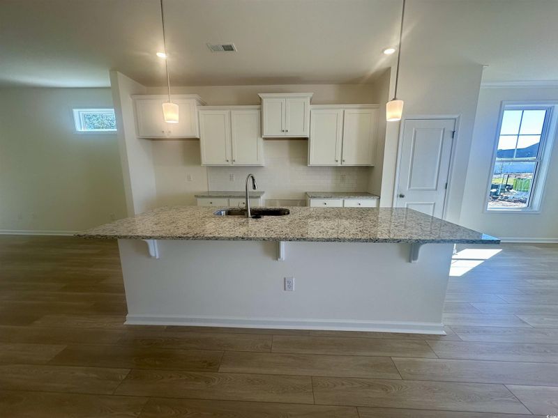 Kitchen featuring healthy amount of natural light, white cabinetry, backsplash, granite countertops, and recessed lighting Kitchen featuring healthy amount of natural light, white cabinetry, backsplash, granite countertops, and recessed lighting