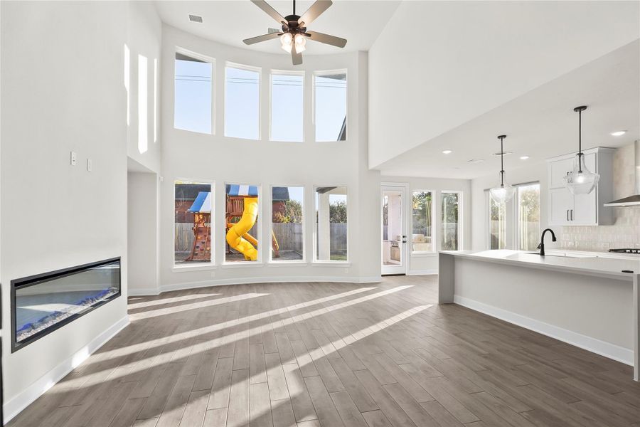 This spacious open-concept living area features high ceilings, large windows for ample natural light, and a modern kitchen with sleek fixtures. The room includes a stylish fireplace and opens to a backyard with a play area, making it ideal for family living and entertaining. This spacious open-concept living area features high ceilings, large windows for ample natural light, and a modern kitchen with sleek fixtures. The room includes a stylish fireplace and opens to a backyard with a play area, making it ideal for family living and entertaining.