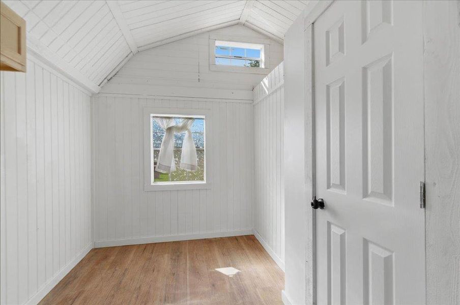 A well-lit interior space with natural light filtering through two windows and showcasing vaulted ceilings.