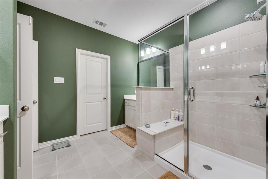 Spacious bathroom featuring a glass-enclosed shower with a built-in bench, tiled walls, and a rainfall showerhead Spacious bathroom featuring a glass-enclosed shower with a built-in bench, tiled walls, and a rainfall showerhead