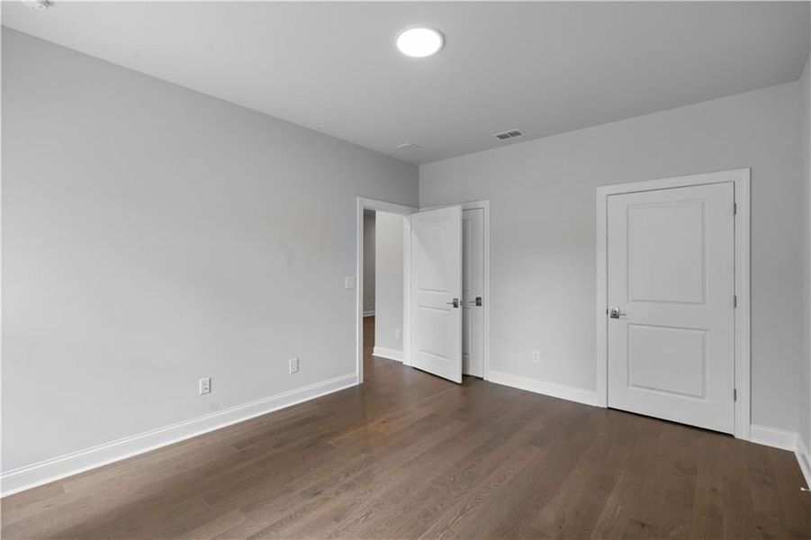 Unfurnished bedroom with dark wood-style floors and baseboards Unfurnished bedroom with dark wood-style floors and baseboards