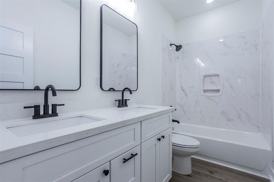 Bathroom featuring a double vanity with matte black fixtures, integrated sinks, white countertops, and shaker-style cabinetry