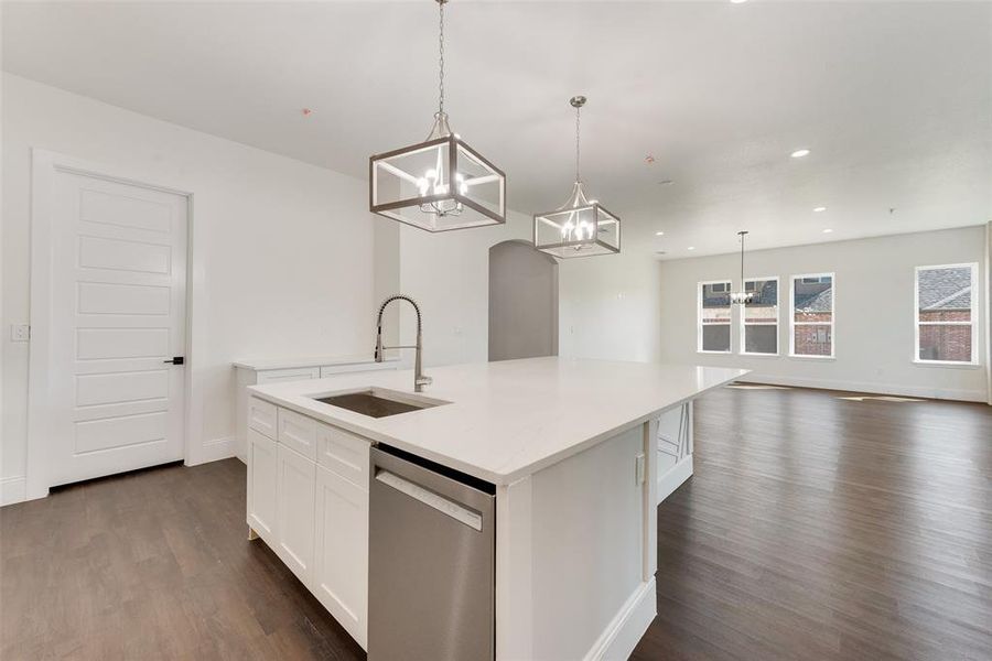 Kitchen island featuring a stainless steel sink with gooseneck faucet, an integrated dishwasher, and a white countertop Kitchen island featuring a stainless steel sink with gooseneck faucet, an integrated dishwasher, and a white countertop