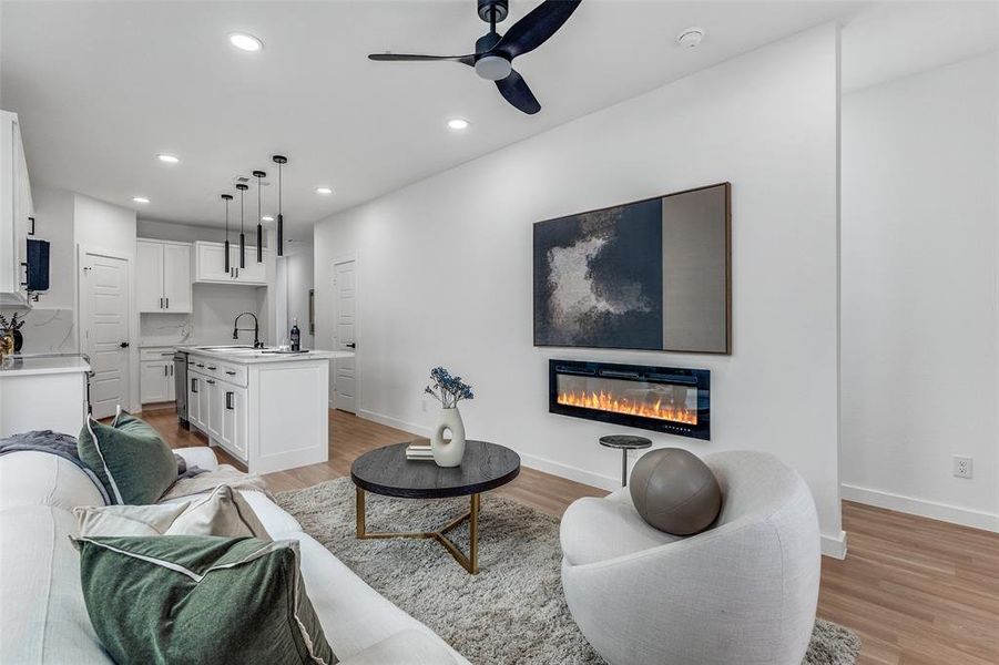 Living area featuring light wood-type flooring, a glass covered fireplace, ceiling fan, and recessed lighting Living area featuring light wood-type flooring, a glass covered fireplace, ceiling fan, and recessed lighting