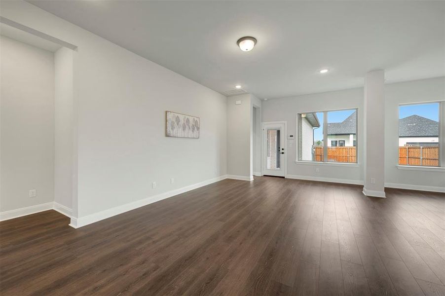 Empty room with dark wood-type flooring and recessed lighting