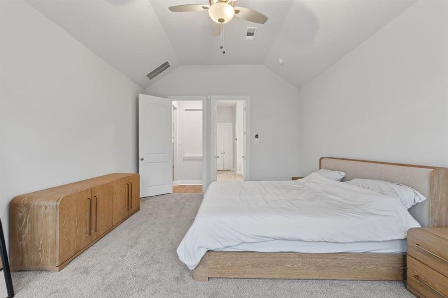 Bedroom featuring vaulted ceiling, a ceiling fan, and light colored carpet Bedroom featuring vaulted ceiling, a ceiling fan, and light colored carpet