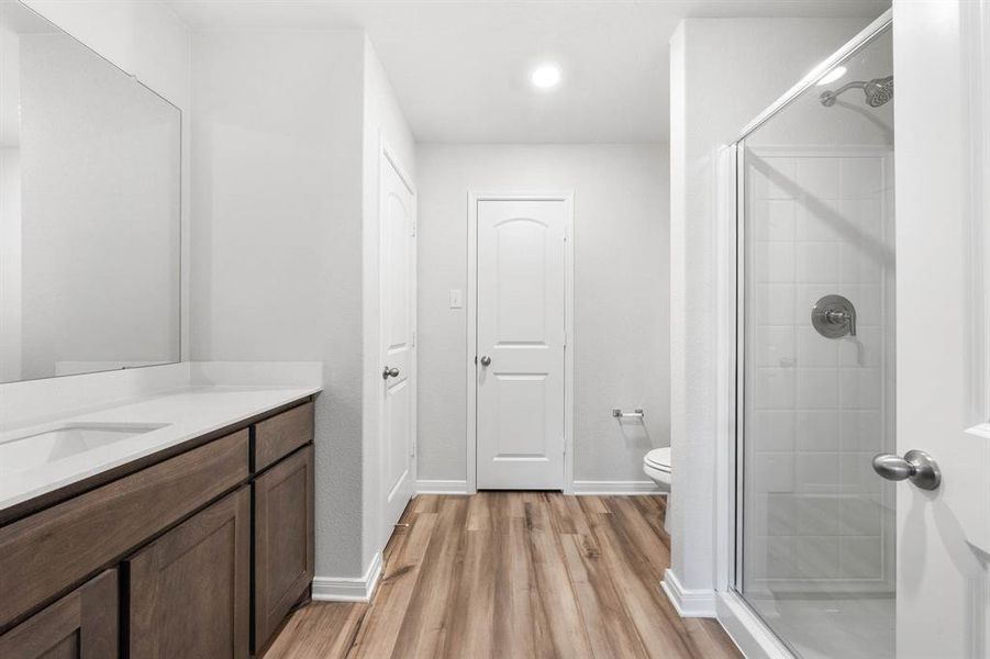 Bathroom with walk in shower, hardwood / wood-style flooring, vanity, and toilet