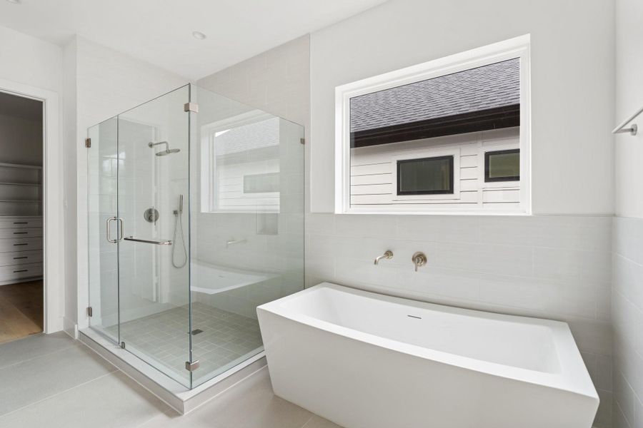 Spa-like primary bath with a frameless glass walk-in shower and a freestanding soaking tub. Spa-like primary bath with a frameless glass walk-in shower and a freestanding soaking tub.