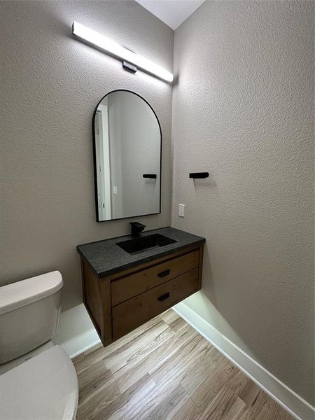 Bathroom with hardwood / wood-style floors, toilet, and vanity