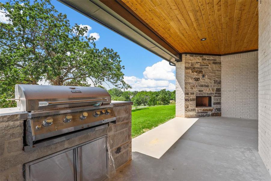 View of patio / terrace with an outdoor stone fireplace and area for grilling