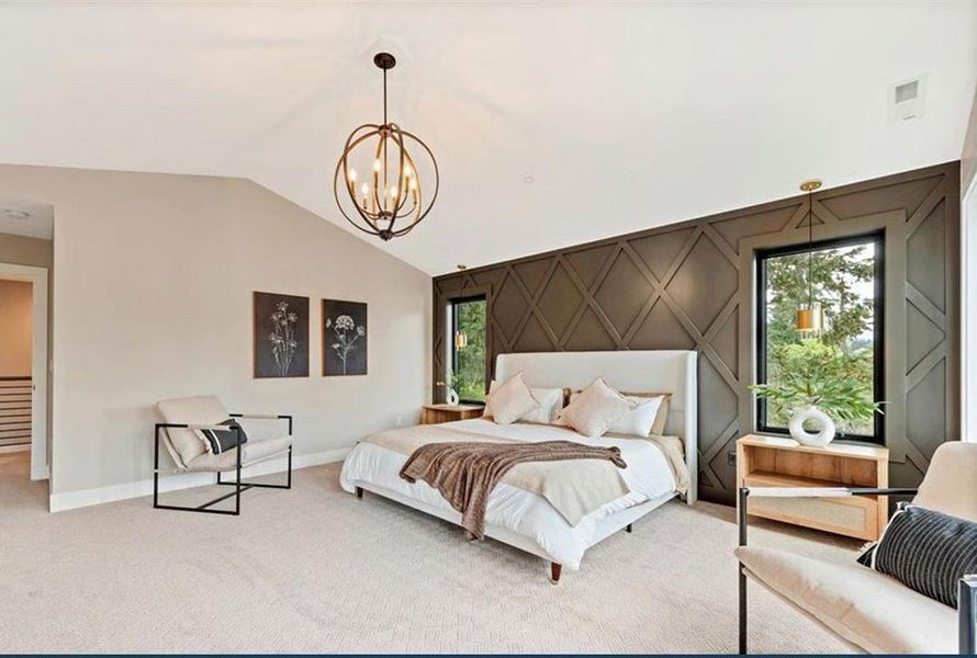 Carpeted bedroom featuring an accent wall, vaulted ceiling, and hanging lights