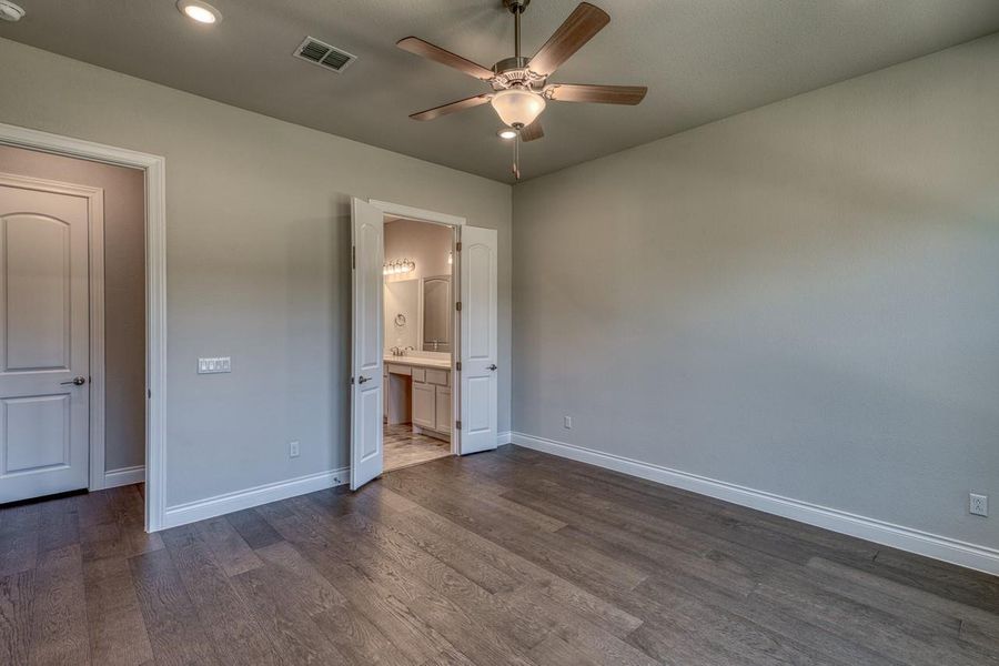 Unfurnished bedroom featuring dark wood finished floors, recessed lighting, ensuite bath, and a ceiling fan