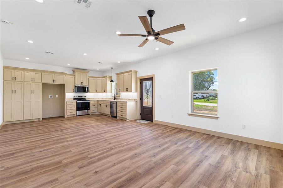Kitchen featuring open floor plan, recessed lighting, cream cabinetry, light wood-style floors, and stainless steel appliances