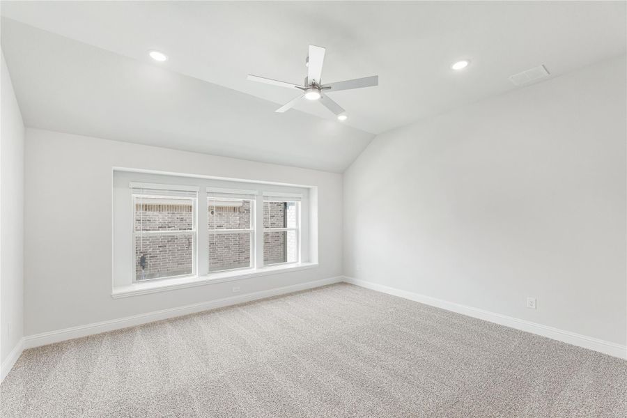 Empty bedroom with vaulted ceiling, ceiling fan, carpet flooring, and triple window with natural light Empty bedroom with vaulted ceiling, ceiling fan, carpet flooring, and triple window with natural light