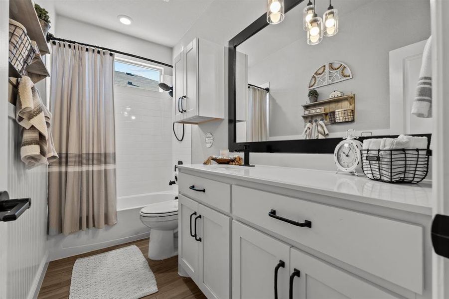 Full bathroom featuring toilet, vanity, hardwood / wood-style flooring, and shower / tub combo with curtain