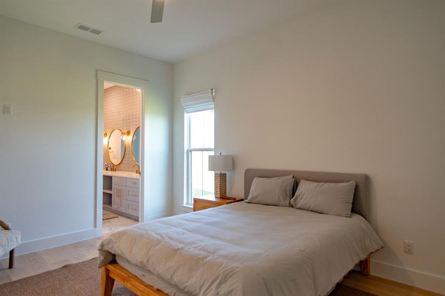 Bedroom with light wood-style floors, connected bathroom, and ceiling fan Bedroom with light wood-style floors, connected bathroom, and ceiling fan