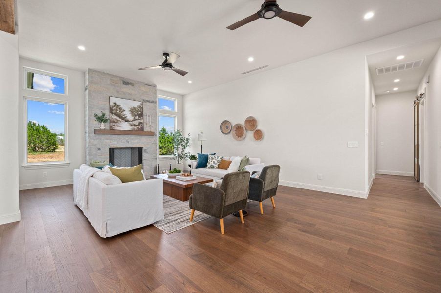 Living room with ceiling fan, wood-style floors, a fireplace, and recessed lighting