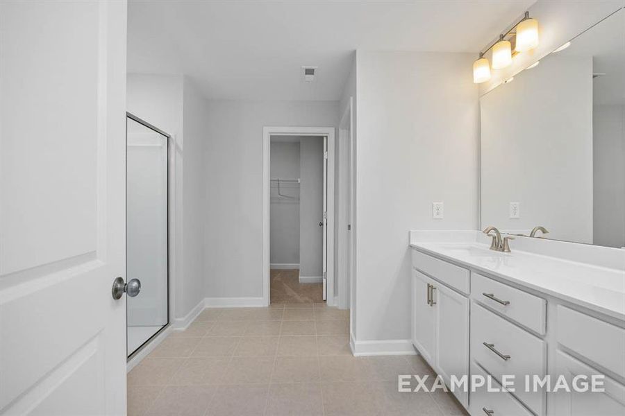 Bathroom featuring tile patterned flooring, vanity, and walk in shower