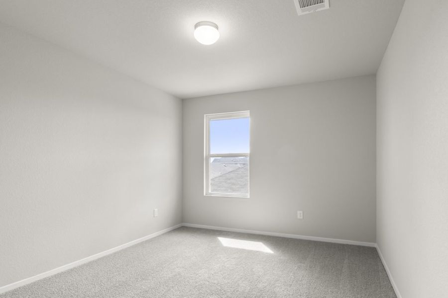 Image of bedroom with light grey carpet and walls with a window
