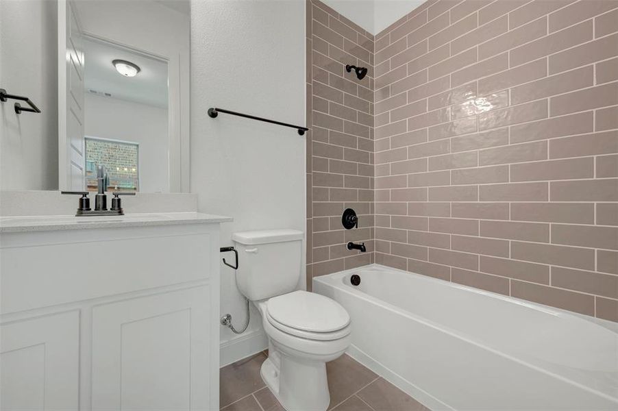 Bathroom featuring a subway tile bath surround, white vanity with integrated sink, black fixtures, and neutral floor tiling Bathroom featuring a subway tile bath surround, white vanity with integrated sink, black fixtures, and neutral floor tiling