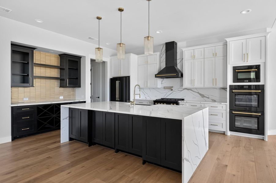 Gleaming stone countertops and warm wood floors define this modern culinary workspace.