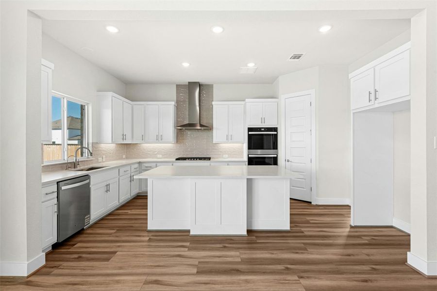 Kitchen featuring white cabinetry, a kitchen island, wall chimney exhaust hood, stainless steel appliances, and recessed lighting