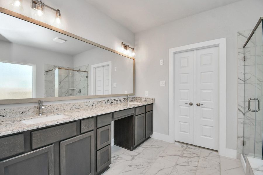 Elevate your daily routine at the elegant vanity, now equipped with double sinks, light countertops, modern hardware, and beautiful vanity lights. Sample photo of completed home with similar floor plan. Actual colors and selections may vary.