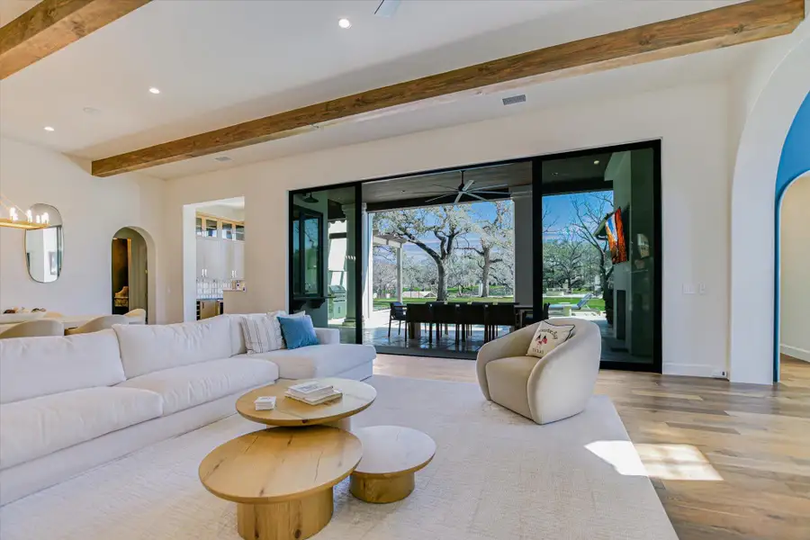 Living room with arched walkways, beam ceiling, recessed lighting, and wood finished floors