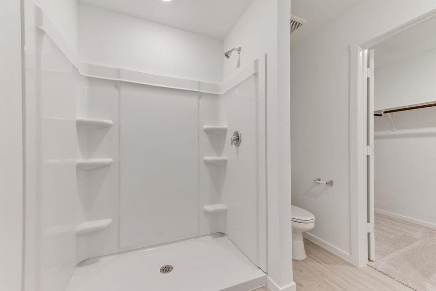 Full bathroom featuring toilet, a stall shower, baseboards, and wood finished floors