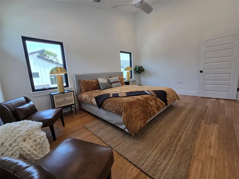 Bedroom featuring wood finished floors, visible vents, a towering ceiling, and ceiling fan Bedroom featuring wood finished floors, visible vents, a towering ceiling, and ceiling fan