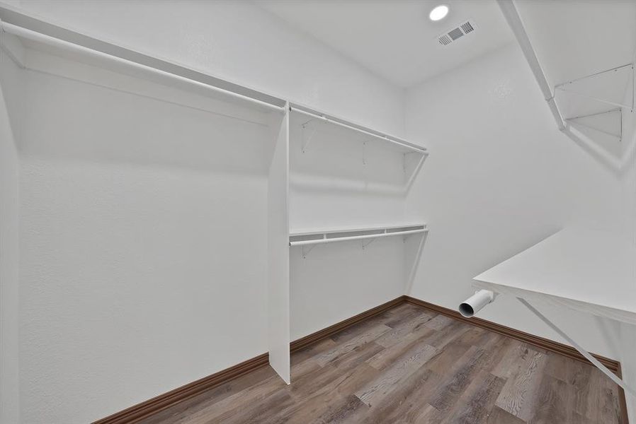 Walk in closet with attic access and wood finished floors