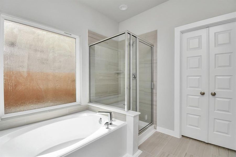 Delight in a spacious walk-in shower enveloped in stylish tile surround, unwind in a separate garden tub adorned with custom detailing, and elevate your daily routine at the elegant vanity, now equipped with double sinks, light countertops, modern hardware.