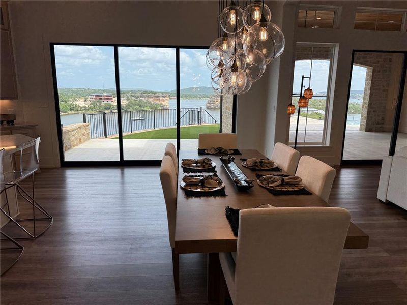 Dining room featuring wood finished floors, a chandelier, and a water view Dining room featuring wood finished floors, a chandelier, and a water view