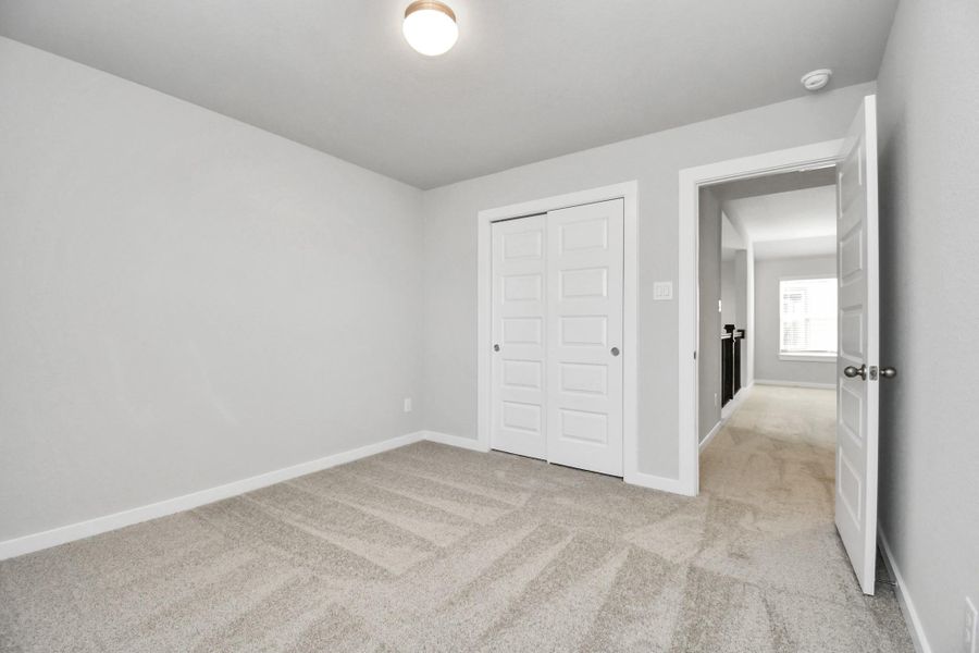 Secondary bedroom features plush carpeting, large windows that let in plenty of natural light, bright paint, and spacious closets. Sample photo of completed home with similar floor plan. Actual colors and selections may vary.