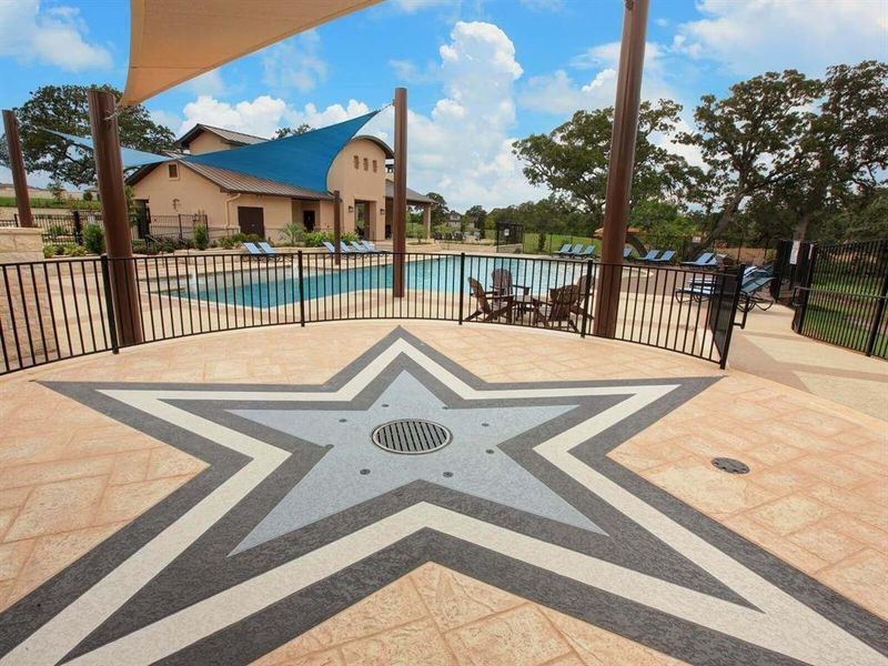 Stone-paved patio detailing leads to a community swimming pool framed by classic metal fencing.
