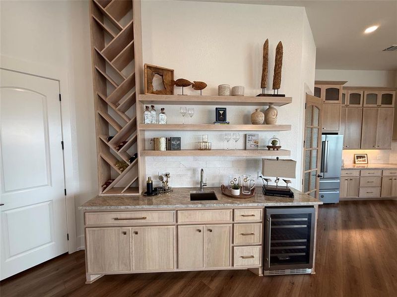 Indoor wet bar with wine cooler, high end refrigerator, dark wood-style flooring, and backsplash Indoor wet bar with wine cooler, high end refrigerator, dark wood-style flooring, and backsplash