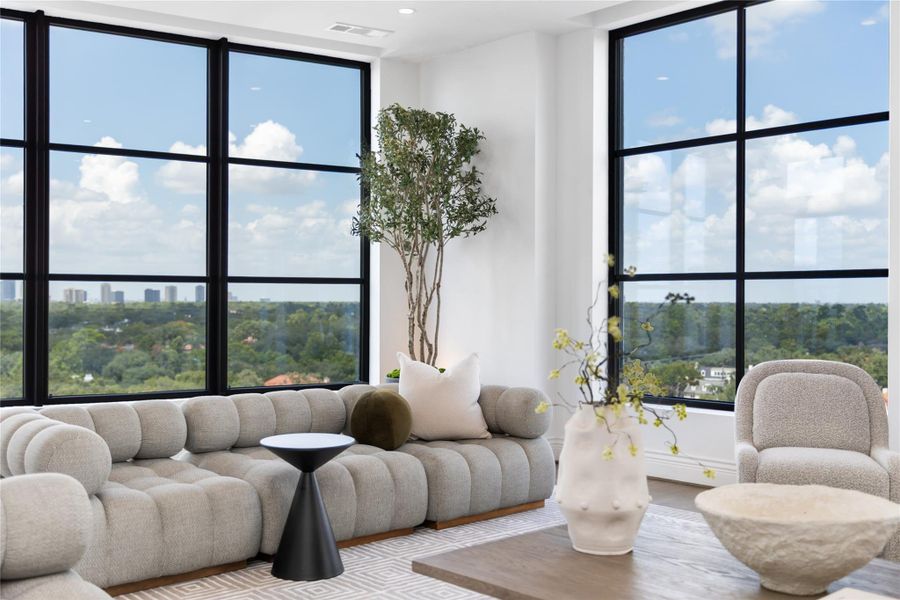 A light-filled living space welcomes you with expansive floor-to-ceiling windows framing sweeping skyline views, creating an inviting setting for both everyday living & entertaining.